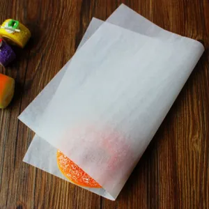 Detail view of translucent greaseproof paper wrapping an orange pastry on wood