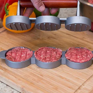 Action shot of 3-hole non-stick burger press molding raw beef patties on wood