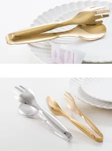 Set of gold and silver stainless steel food tongs with mirror finish on white plates