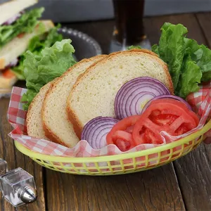 Bright yellow plastic fast food basket with bread and vegetables on rustic wooden table
