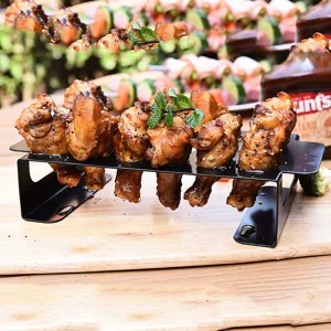 Close-up of a black 18-hole stainless steel grill rack holding grilled chicken legs