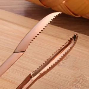 Gros plan de pinces à steak professionnelles en acier inoxydable or rose avec bords dentelés