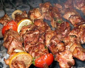 Macro detail view of succulent meat skewers with lemon and tomato on BBQ metal skewers