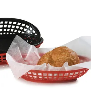 Close-up of a red plastic fast food basket with a croissant and wax paper liner.