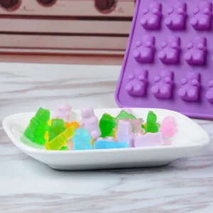 Makroansicht von bunten Gummibärchen in einer Schale neben einer lila Silikonform.