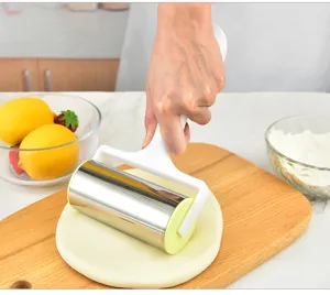 Handheld stainless steel dough roller used on a wooden board for baking details