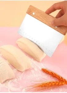 Detailed view of a stainless steel dough scraper with wooden handle and metric ruler scale