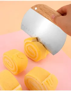 Detail shot of stainless steel dough scraper with scale cutting soft yellow cake rolls