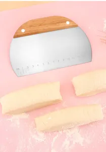 Close-up of semi-circular stainless steel dough scraper with wooden handle and ruler