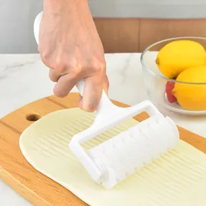 White plastic lattice roller cutter tool for baking pizza and pastry dough on board