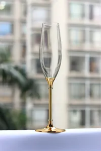 Close-up of elegant champagne glass with a gold metallic stem and crystal accents