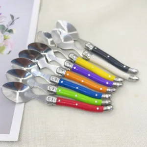 Close-up of eight stainless steel spoons with colorful polka dot plastic handles