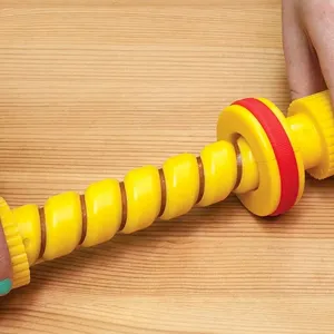 Close-up of yellow spiral hot dog cutter slicing a sausage on a wooden board