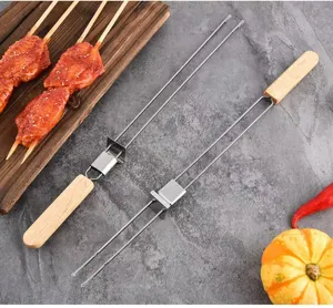 Detail von zweizinkigen Grillspießen aus Edelstahl mit Holzgriffen auf Steinboden