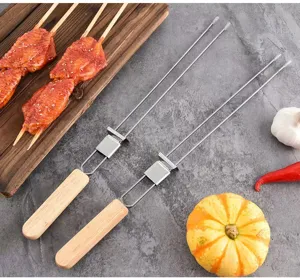 Detail von Doppelzinken Edelstahl BBQ Spießen mit Holzgriffen auf grauem Hintergrund.