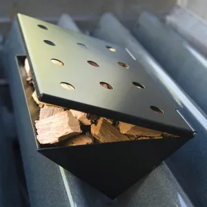 Detalle de caja ahumadora triangular negra con virutas de madera para barbacoas