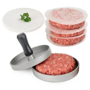 Close-up of manual metal hamburger patty press mold with raw meat and round wax paper