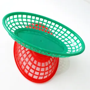 Close-up view of green and red plastic oval mesh trays for fast food or desktop storage.