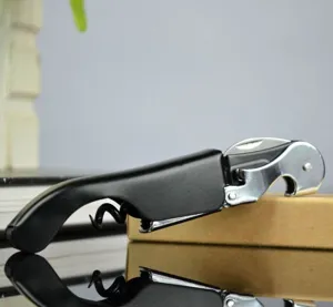 Macro detail of a sleek black seahorse style wine corkscrew on a reflecting surface.