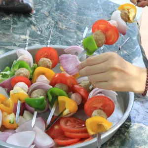 Nahaufnahme von Edelstahl-Grillspießen, die buntes Fleisch und Gemüse aufspießen