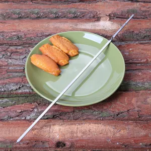 Nahaufnahme eines langlebigen Edelstahl-Grillspießes auf einem grünen Teller mit Essen