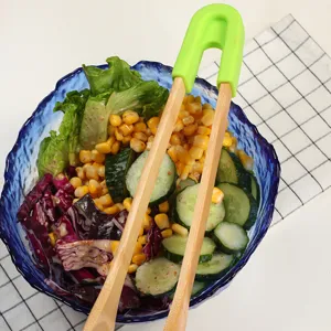 Detachable wooden food tongs with green handle used in a salad bowl for kitchen serving