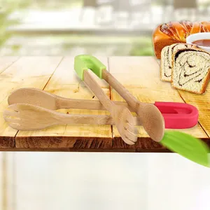 Detailed view of bamboo salad tongs with green and red silicone handles on a wooden table