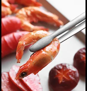 Macro close-up view of stainless steel kitchen tongs gripping a fresh cooked shrimp