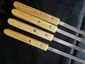 Detailansicht von vier Grillspießen aus Edelstahl mit Griffen aus echtem Eichenholz
