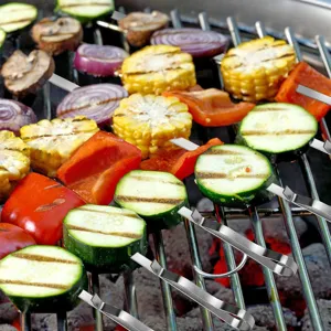 Primer plano de brochetas de barbacoa onduladas de acero inox con verduras asadas en parrilla