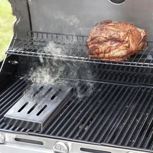 Close-up detail of a stainless steel smoker box emitting smoke on a gas grill rack