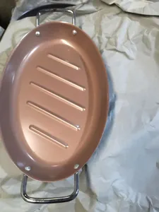 Macro view of oval copper non-stick roasting pan with ridged surface and handles