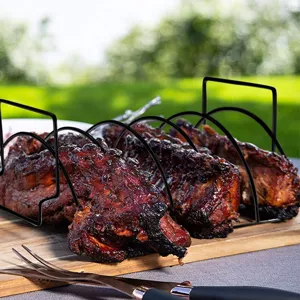 Detailed macro shot of a black non-stick metal rib rack holding grilled pork ribs outdoors