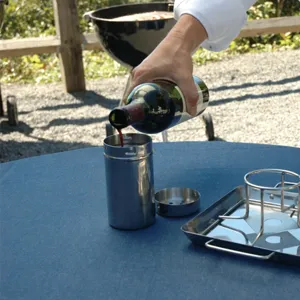 Pouring wine into a stainless steel chicken roaster for BBQ flavor infusion