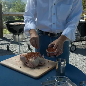 Detailed view of preparing a whole chicken for a stainless steel beer can BBQ roaster rack.