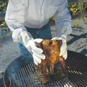 Close-up view of a stainless steel beer can chicken roaster on a barbecue grill.