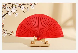 Elegante abanico plegable rojo en soporte de madera con flores blancas de fondo