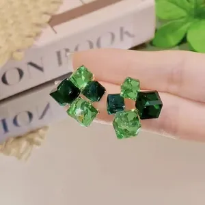 Close-up of elegant green crystal square stud earrings with cluster design