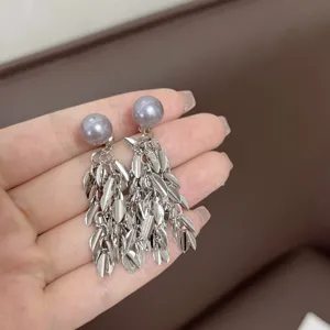 Dettaglio ravvicinato di orecchini a nappa con foglie d'argento e perle grigio viola.