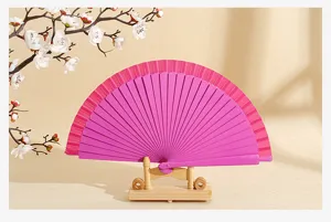 Vista detallada de un abanico plegable de madera estilo español en color rosa vibrante.
