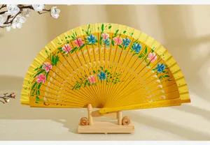 Detalle de abanico español de madera pintado a mano con flores sobre fondo amarillo