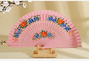Detalle de abanico español de madera pintado a mano rosa sobre un soporte de madera natural