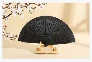 Vista detallada de un elegante abanico español negro en un soporte de madera.