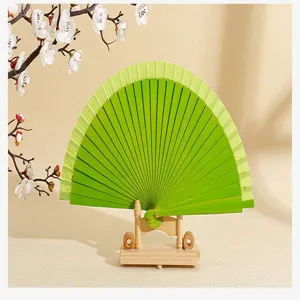 Primer plano de un abanico plegable español de madera verde vibrante en un soporte