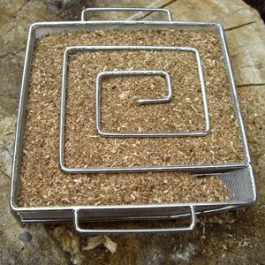 Top view of square stainless steel smoker box filled with wood chips on a tree stump
