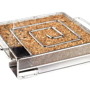 Close-up of a stainless steel square cold smoke generator smoking with fine wood dust chips