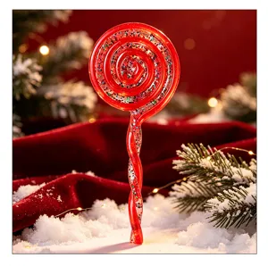 Detailansicht eines glitzernden roten Spiral-Lutscher-Weihnachtsbaumanhängers im Schnee