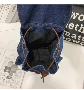 Detail view of denim backpack interior featuring a spacious black lining and drawstring closure.