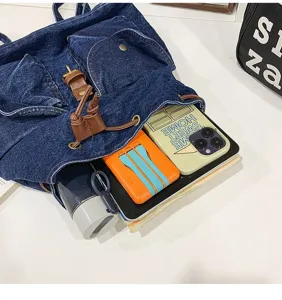 Detailed view of blue denim backpack showing large capacity with lifestyle items