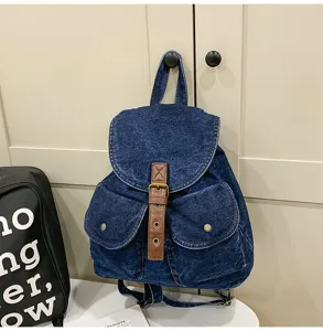 Detail view of a vintage blue denim backpack with brown faux leather buckle straps